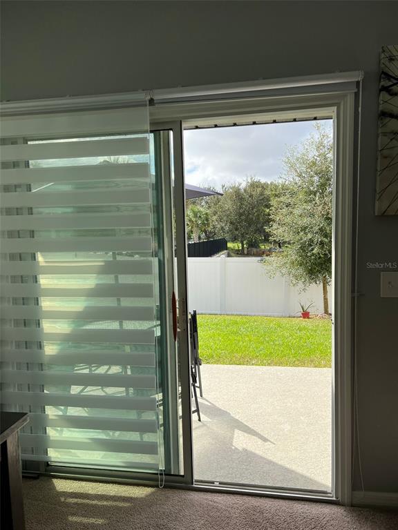 A sliding glass door opens to a concrete patio and a fenced backyard with trees — 863 GRANDIN STREET, DAVENPORT, FL