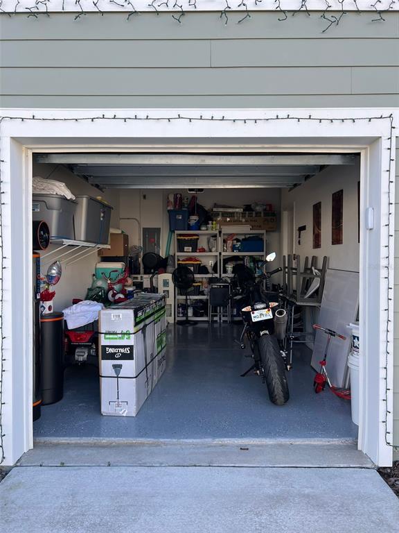 A view into a residential garage with a motorcycle, storage shelves, and a large box — 863 GRANDIN STREET, DAVENPORT, FL