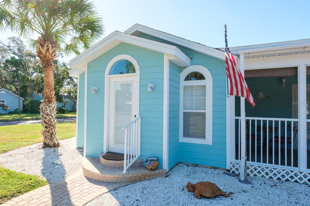 A turquoise house exterior features a white front door, arched windows, and a palm tree — 5302 28TH AVENUE S, GULFPORT, FL