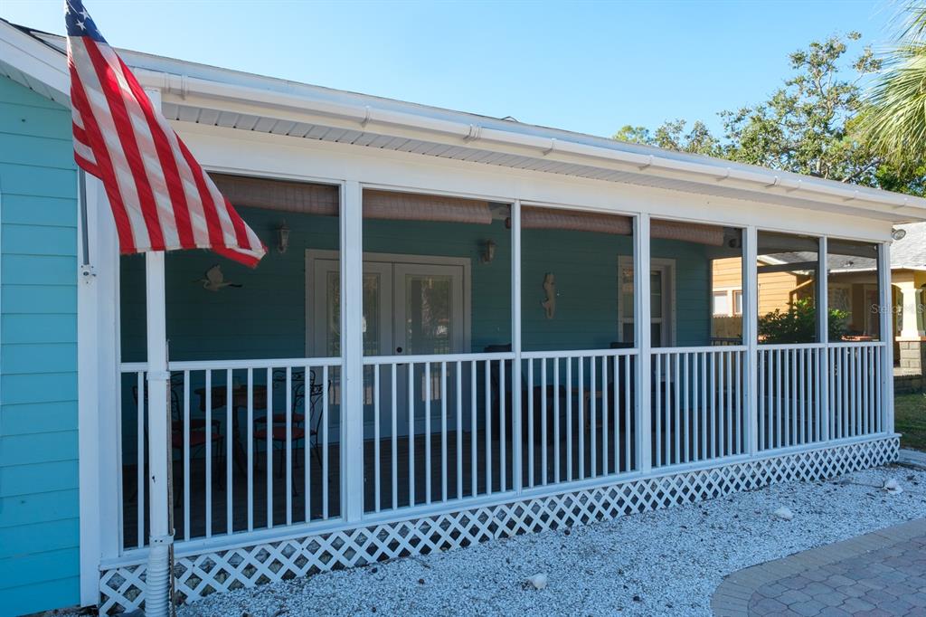 A screened-in porch with white railings and lattice skirting attached to a blue house — 5302 28TH AVENUE S, GULFPORT, FL