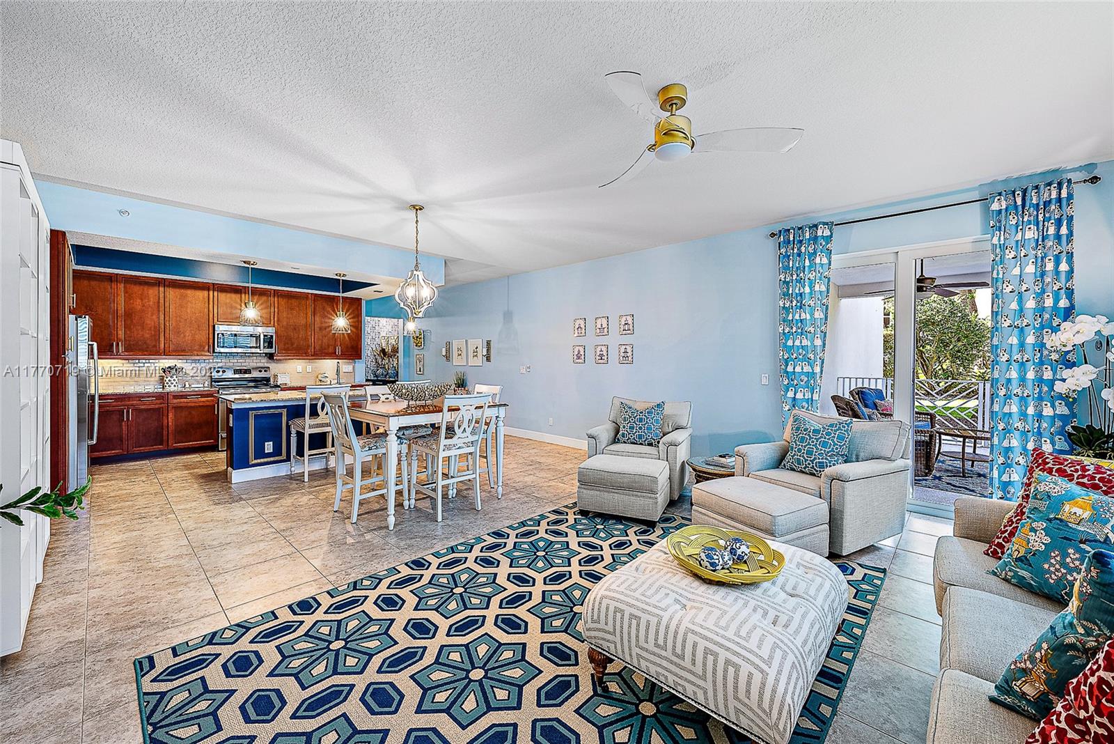 An open-concept living and dining area features tile floors, blue walls, and a kitchen — 1015 S Bay Colony Drive S Slip 17, Juno Beach FL 33408, JUNO BEACH, FL