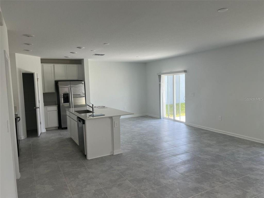 A kitchen with white cabinets and an island opens into a spacious living area — 1756 WHITE WATER COURT, DAVENPORT, FL