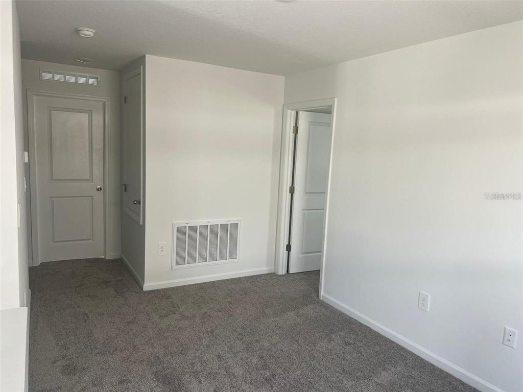A carpeted room features two white doors, a wall vent, and several electrical outlets — 1756 WHITE WATER COURT, DAVENPORT, FL