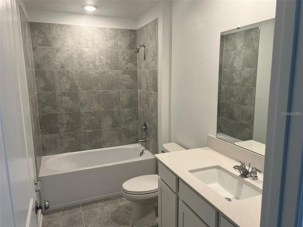A bathroom features a tub-shower combination with gray tile, a vanity, and a toilet — 1756 WHITE WATER COURT, DAVENPORT, FL
