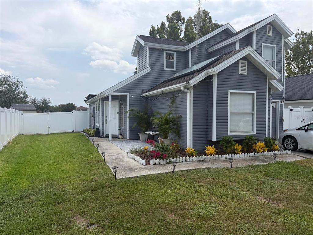 A two-story house with gray siding, a white fence, and a front patio area — 9924 SURREY RIDGE ROAD, ORLANDO, FL