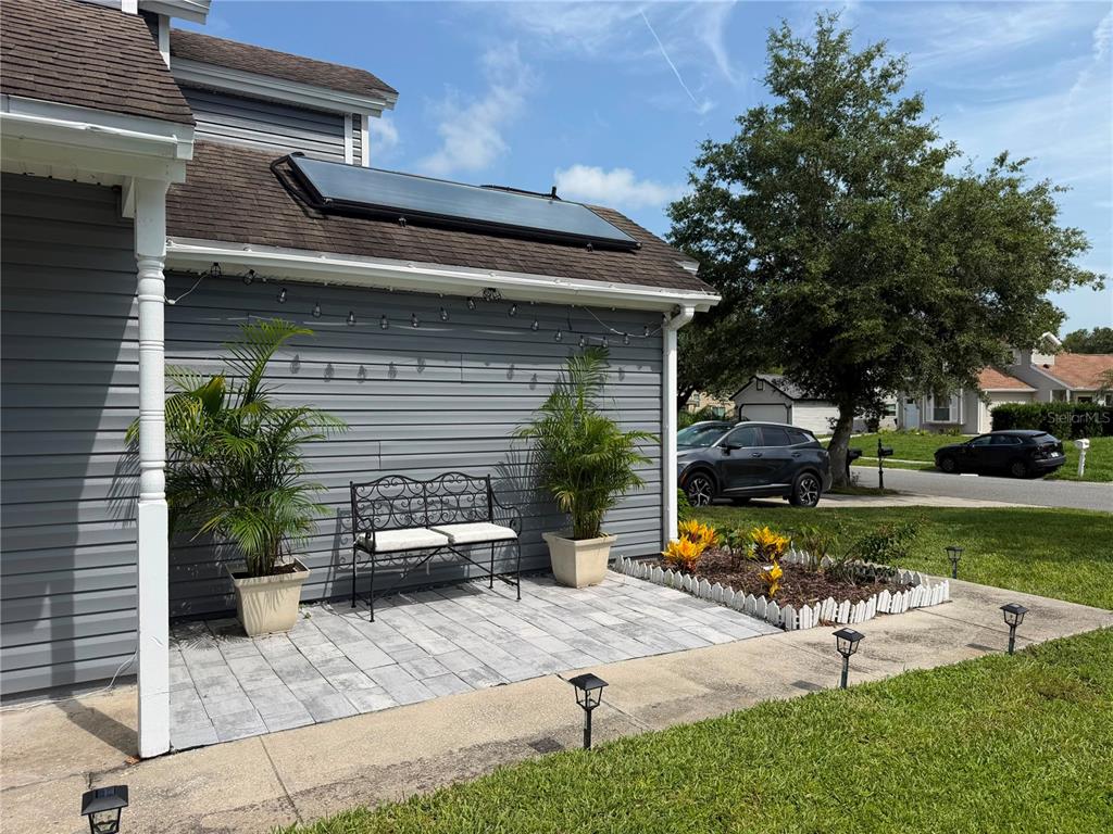 A gray-sided house features a patio with a metal bench, potted plants, and solar panels — 9924 SURREY RIDGE ROAD, ORLANDO, FL