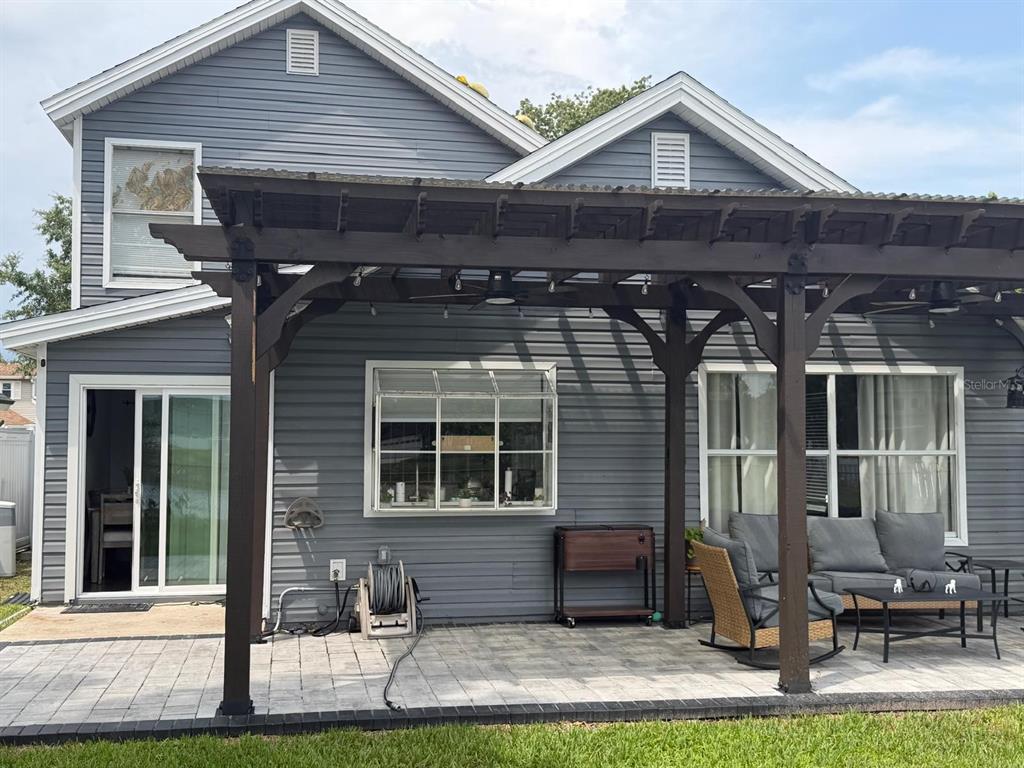 A gray-sided house with a large wooden pergola covering a paved patio area — 9924 SURREY RIDGE ROAD, ORLANDO, FL