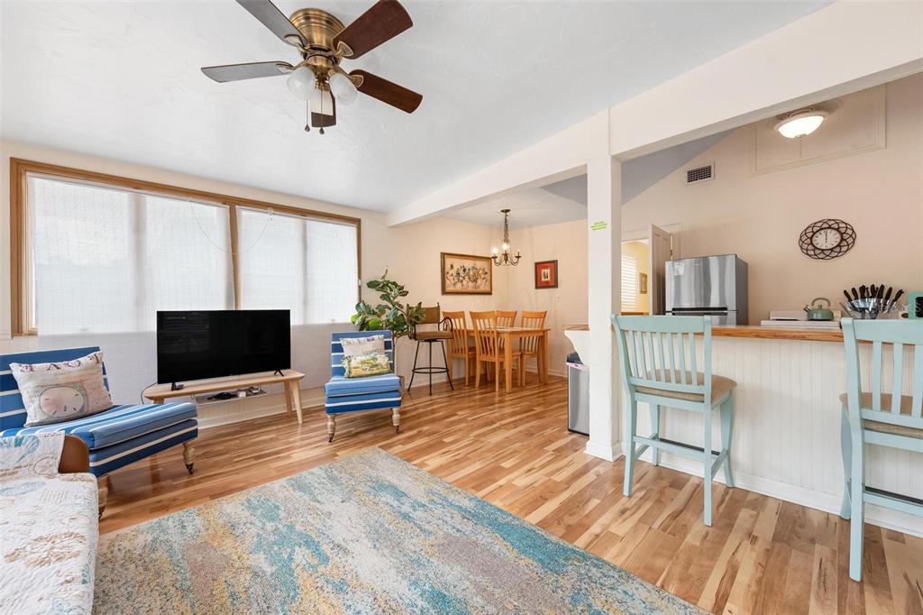 An open-concept living and dining area features hardwood floors, a ceiling fan, and bar seating — 2245 BAHIA VISTA STREET, SARASOTA, FL