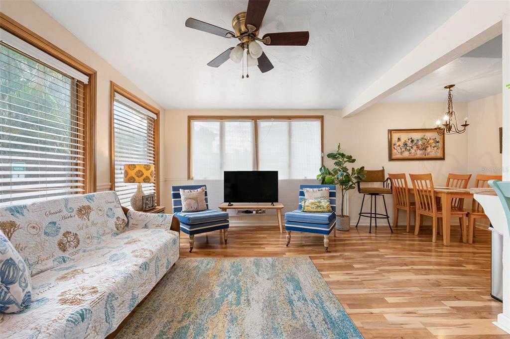 A living room with hardwood floors, a ceiling fan, blue accent chairs, and a dining area — 2245 BAHIA VISTA STREET, SARASOTA, FL