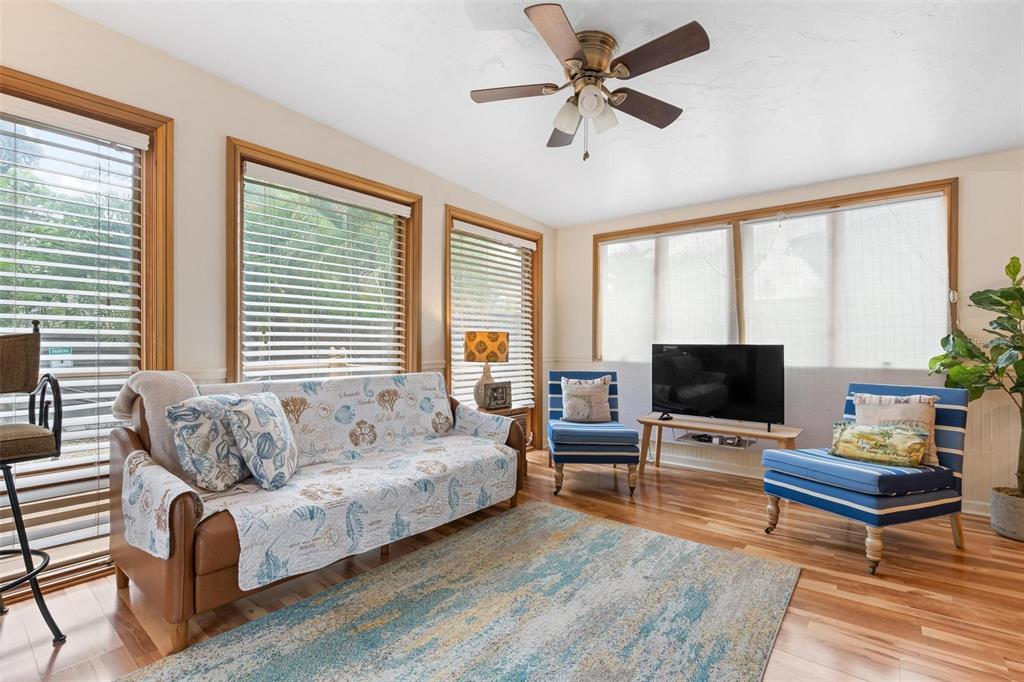 A living room with a sofa, two blue chairs, a television, and wood flooring — 2245 BAHIA VISTA STREET, SARASOTA, FL