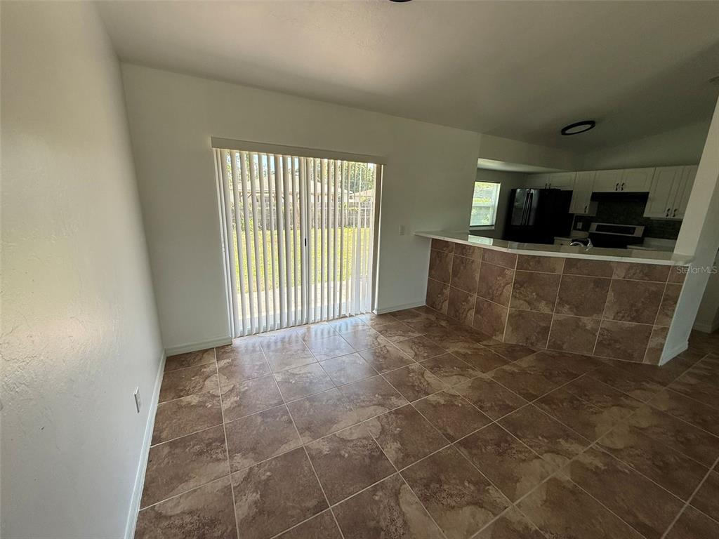 A dining area with tiled floors, a sliding glass door, and a tiled breakfast bar — 2723 YACOLT AVENUE, NORTH PORT, FL