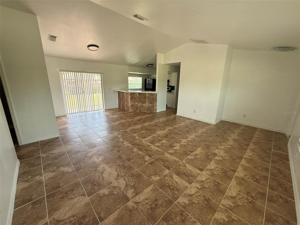 An open-concept living area features tiled floors, a tiled breakfast bar, and sliding glass doors — 2723 YACOLT AVENUE, NORTH PORT, FL