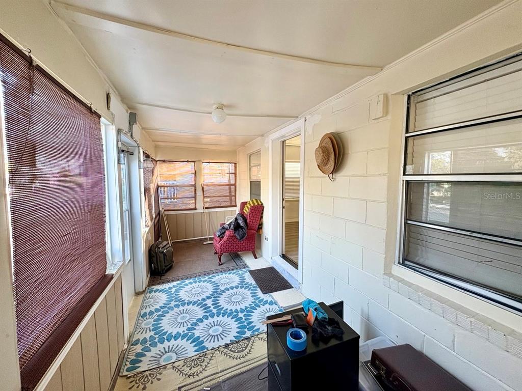 A sunroom features a patterned area rug, a red armchair, and white painted brick walls — 524 E LIME STREET, TARPON SPRINGS, FL