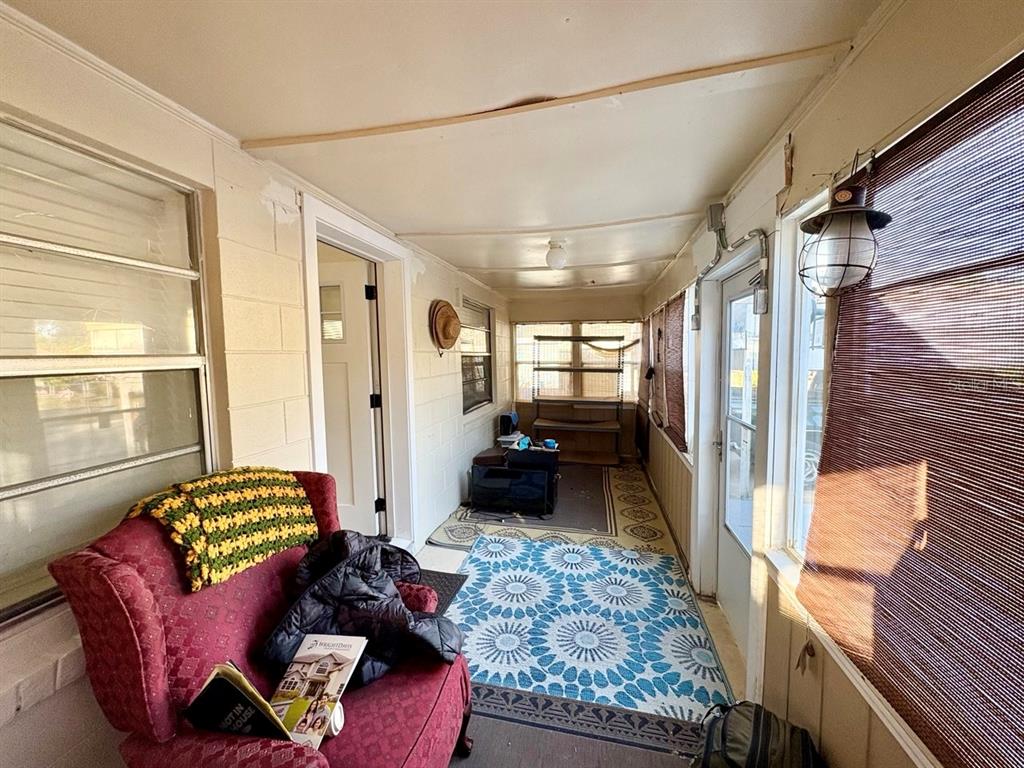 A sunroom features a red armchair, a blue patterned rug, and large windows with blinds — 524 E LIME STREET, TARPON SPRINGS, FL