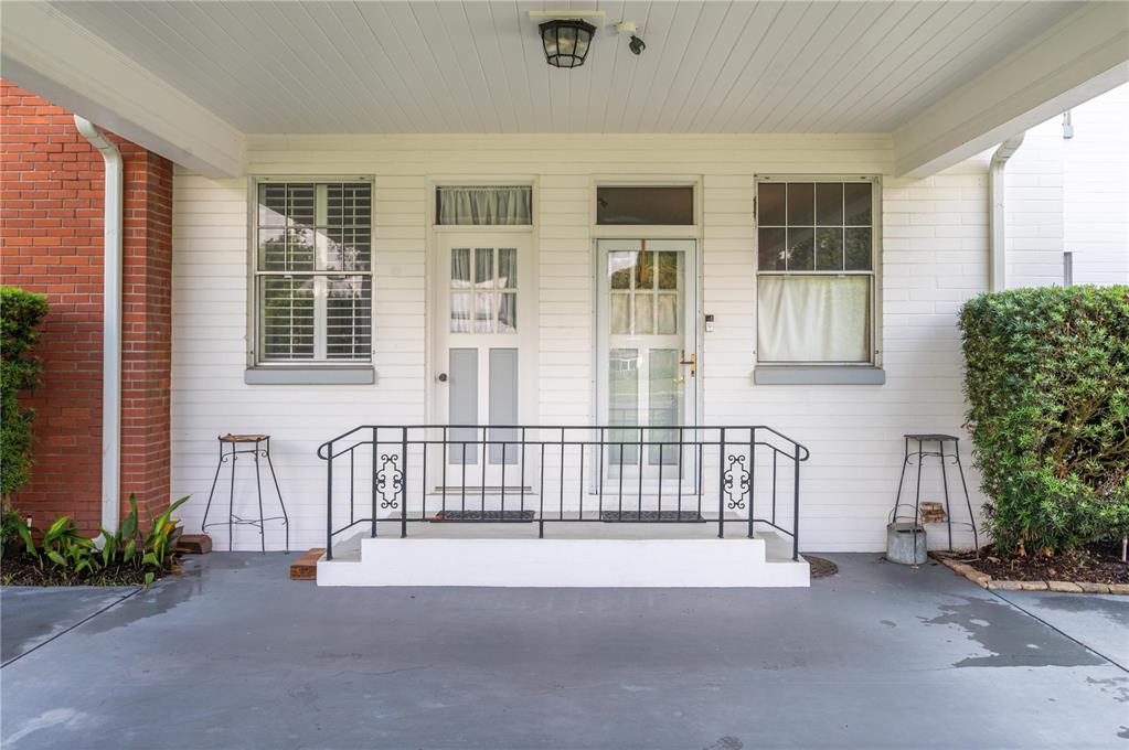 A covered porch features a white brick exterior, two entry doors, and a metal railing — 300 3RD STREET NE, FORT MEADE, FL