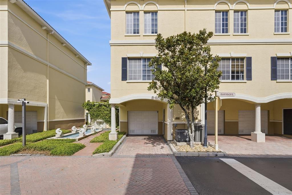 A multi-story townhouse exterior features a paved driveway, a garage, and a small fountain — 113 GRAND BEACH PLACE, TAMPA, FL