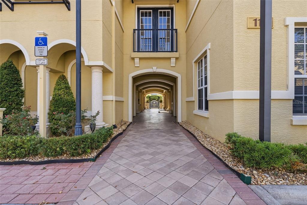 A paved walkway leads through an arched breezeway between two yellow stucco buildings — 113 GRAND BEACH PLACE, TAMPA, FL