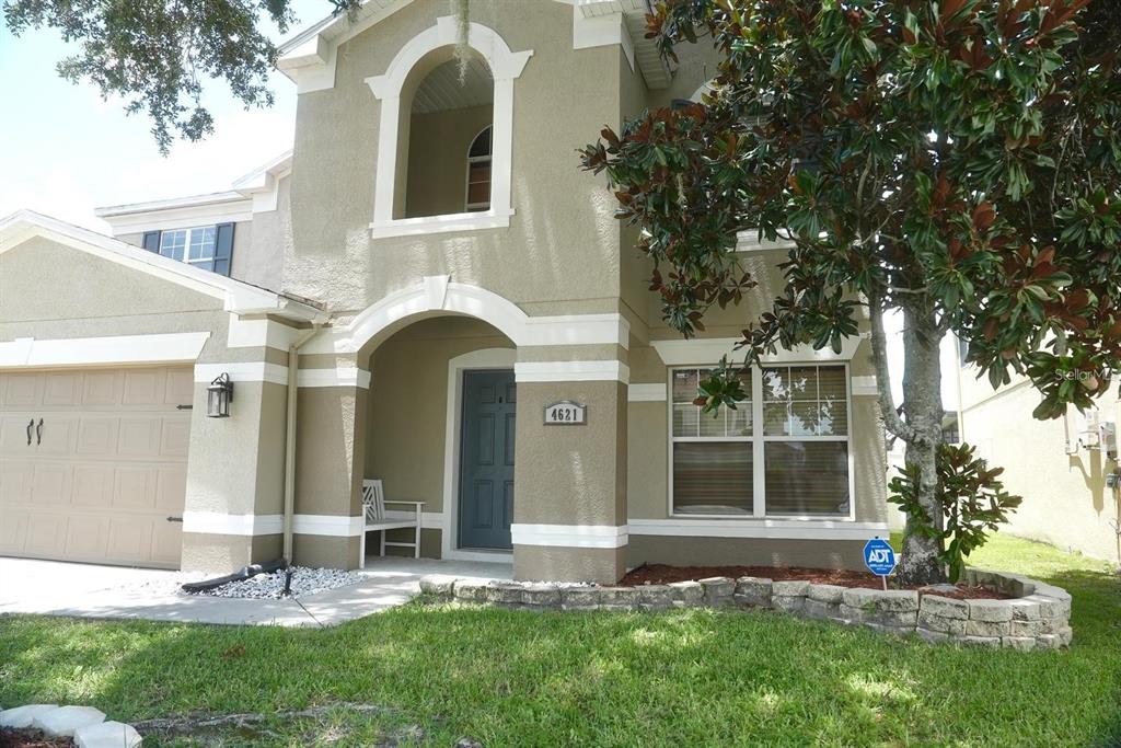 A two-story house with a beige stucco exterior, a garage, and a small front porch — 4621 YELLOW BAY DRIVE, KISSIMMEE, FL
