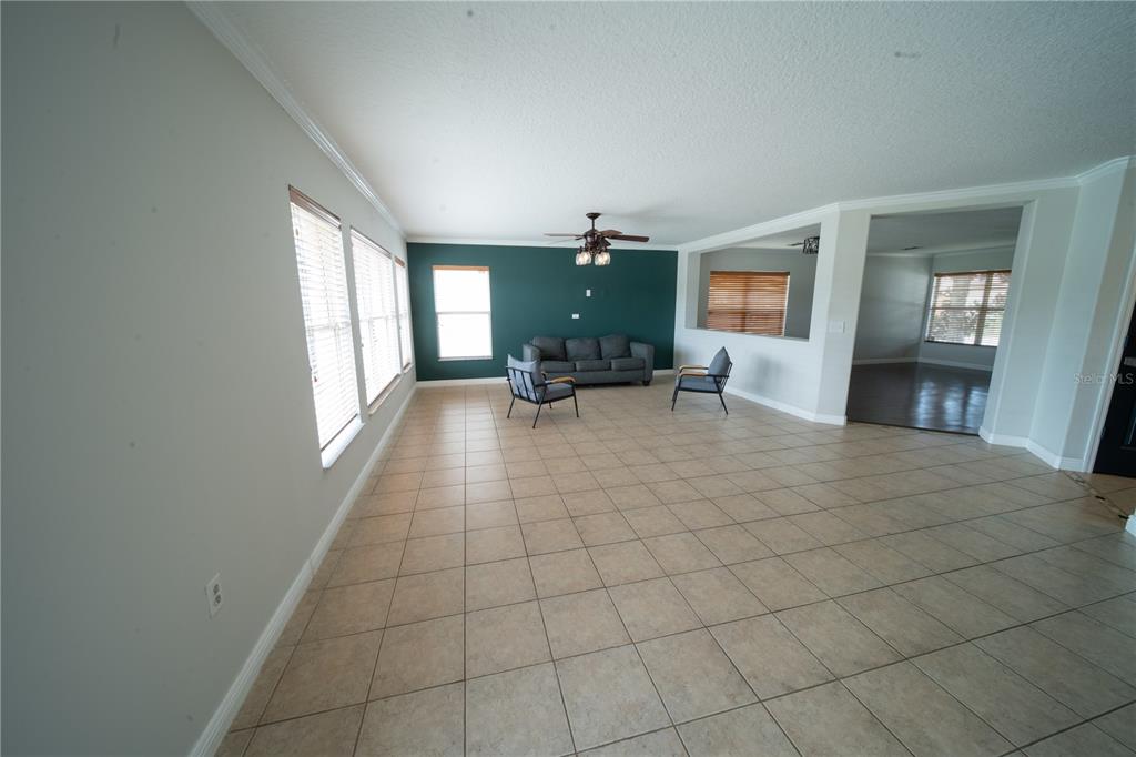 A spacious living room features light tile floors, a dark accent wall, and large windows — 4621 YELLOW BAY DRIVE, KISSIMMEE, FL