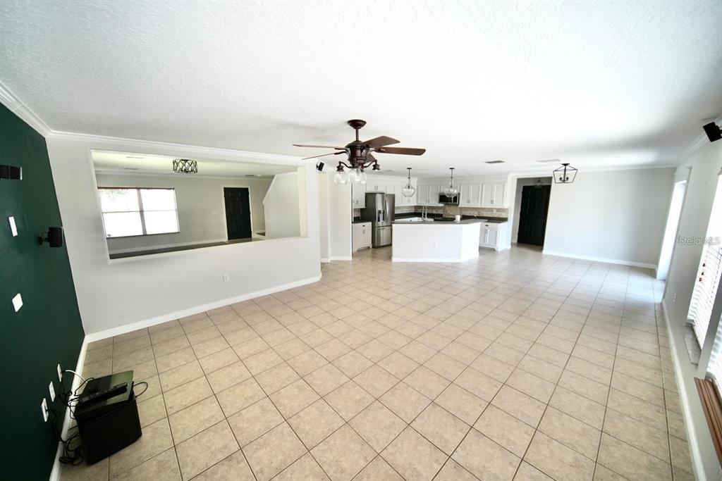 An open-concept living area with tile flooring, a ceiling fan, and a kitchen with white cabinets — 4621 YELLOW BAY DRIVE, KISSIMMEE, FL
