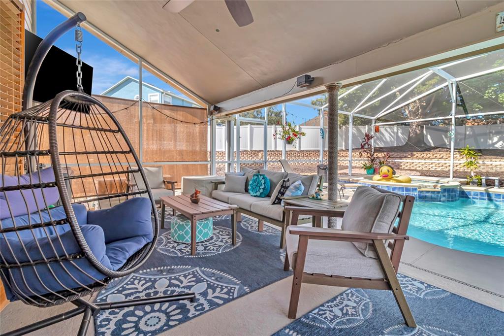 A screened-in patio features a pool, lounge seating, and a hanging egg chair — 10414 MESA LANE, CLERMONT, FL
