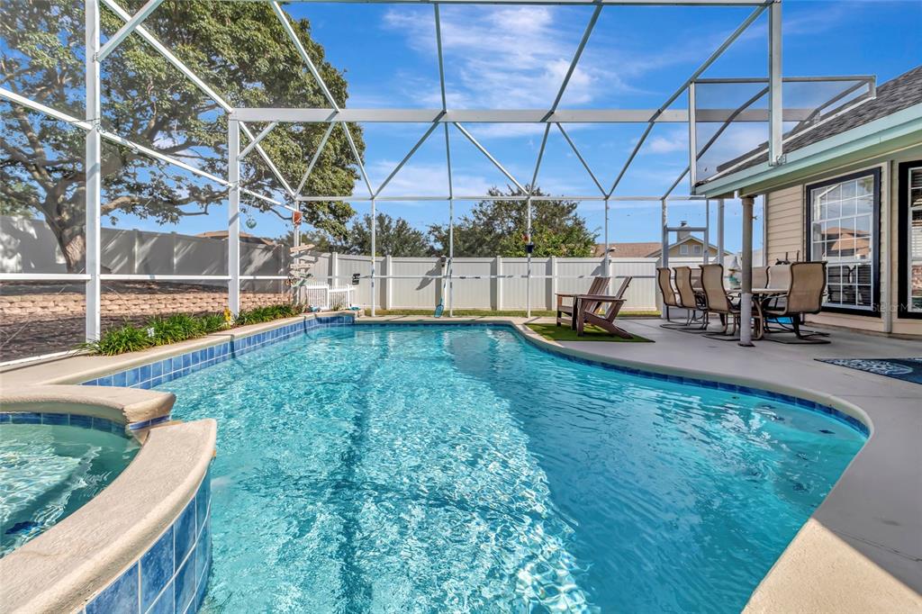 A screened-in swimming pool and spa with a patio dining area and white vinyl fencing — 10414 MESA LANE, CLERMONT, FL