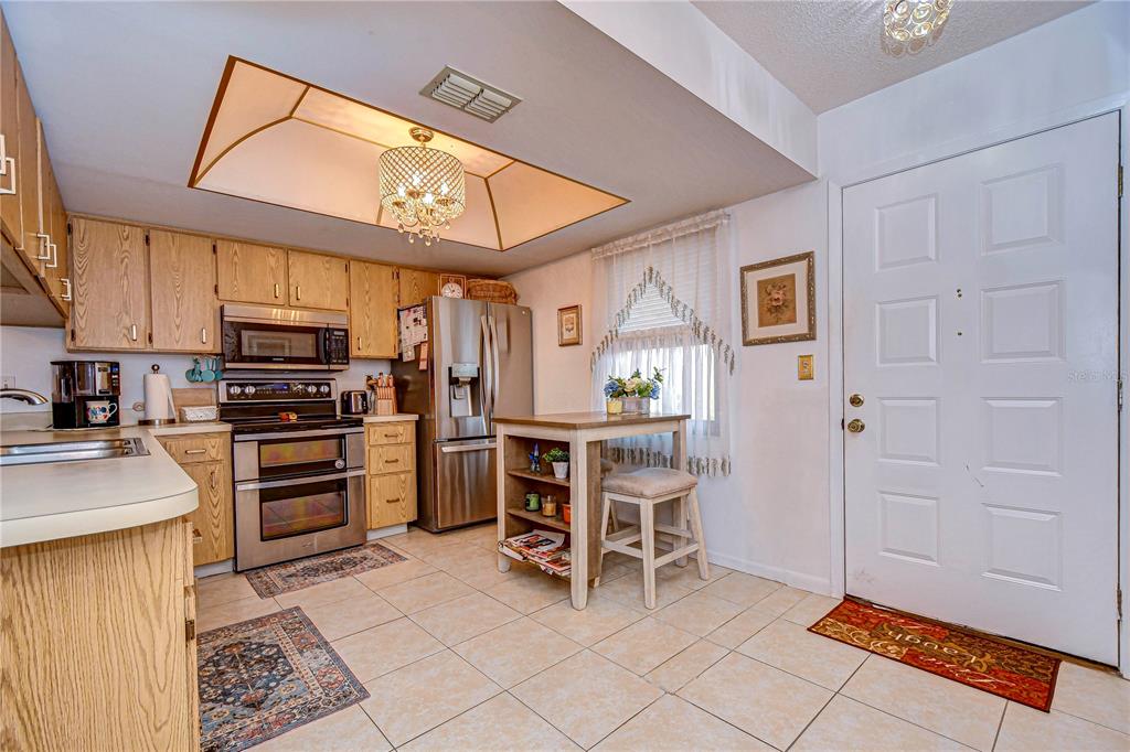 A bright entryway features tile flooring, a blue cabinet, and a small wooden dining table — 38351 IRONWOOD PLACE UNIT NA, ZEPHYRHILLS, FL