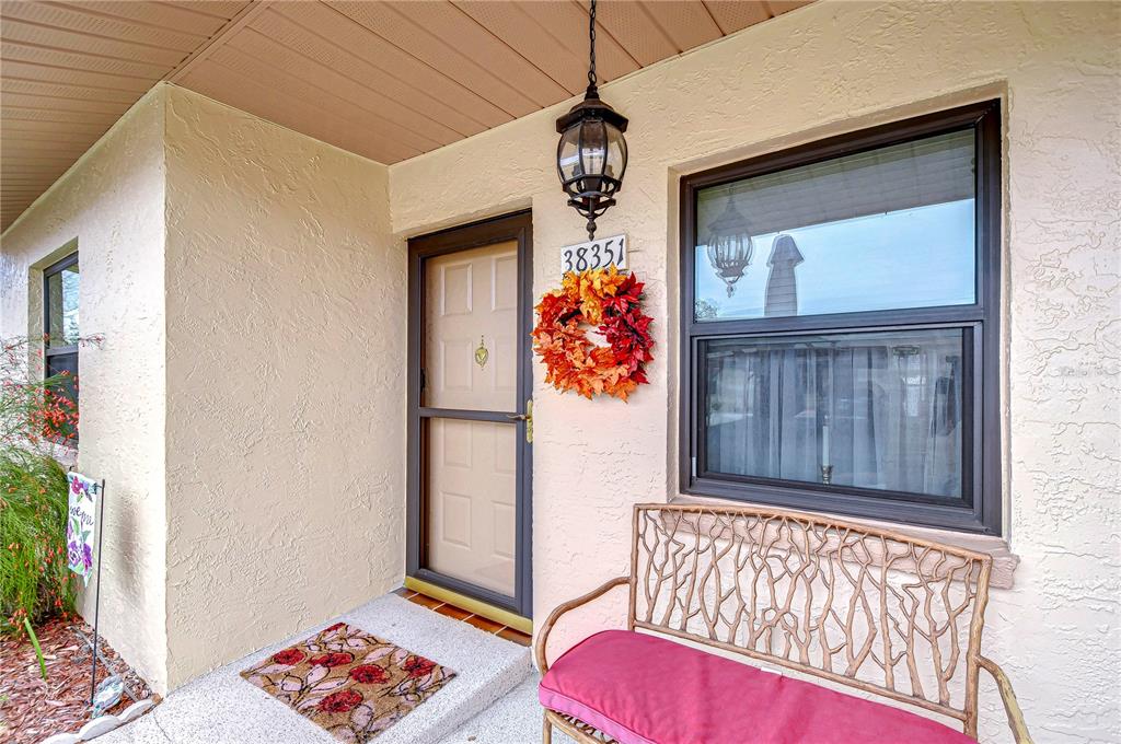 A kitchen features oak cabinets, stainless steel appliances, and a pass-through window to the living area — 38351 IRONWOOD PLACE UNIT NA, ZEPHYRHILLS, FL