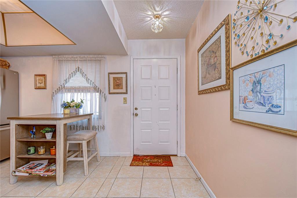 A kitchen features light wood cabinets, stainless steel appliances, a center island, and tile flooring — 38351 IRONWOOD PLACE UNIT NA, ZEPHYRHILLS, FL
