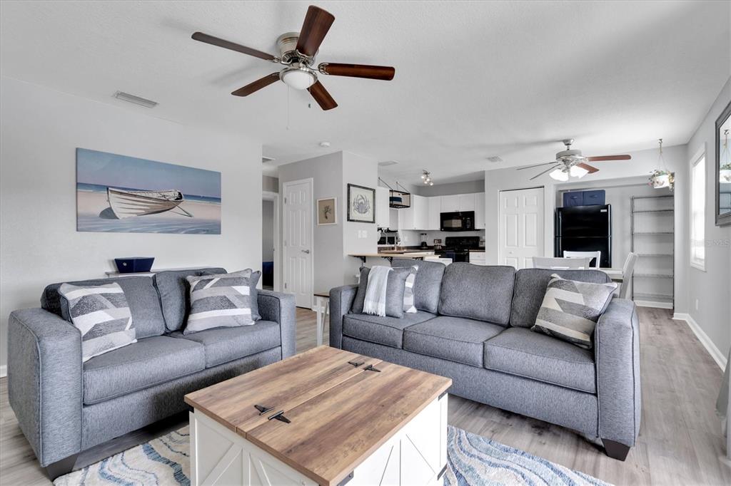 A living room features gray sofas, a wood coffee table, and an open kitchen area — 102 POMPANO DRIVE SE UNIT C, ST PETERSBURG, FL