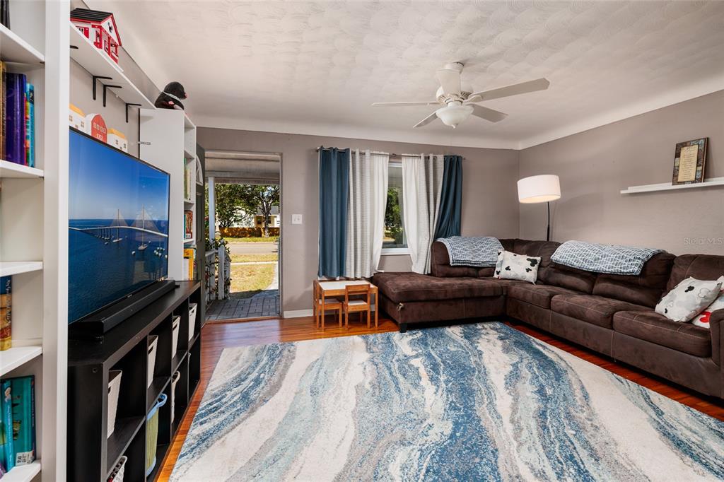 A living room features a brown sectional sofa, a blue patterned rug, and a television — 4939 DR MARTIN LUTHER KING JR STREET N, ST PETERSBURG, FL