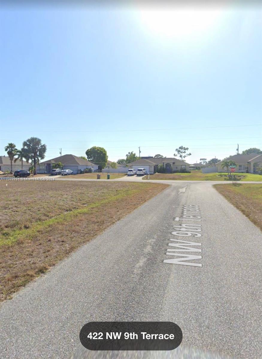 A paved road leads toward several suburban houses surrounded by open, grassy lots — 422 NW 9th Terr, Cape Coral FL 33993, CAPE CORAL, FL