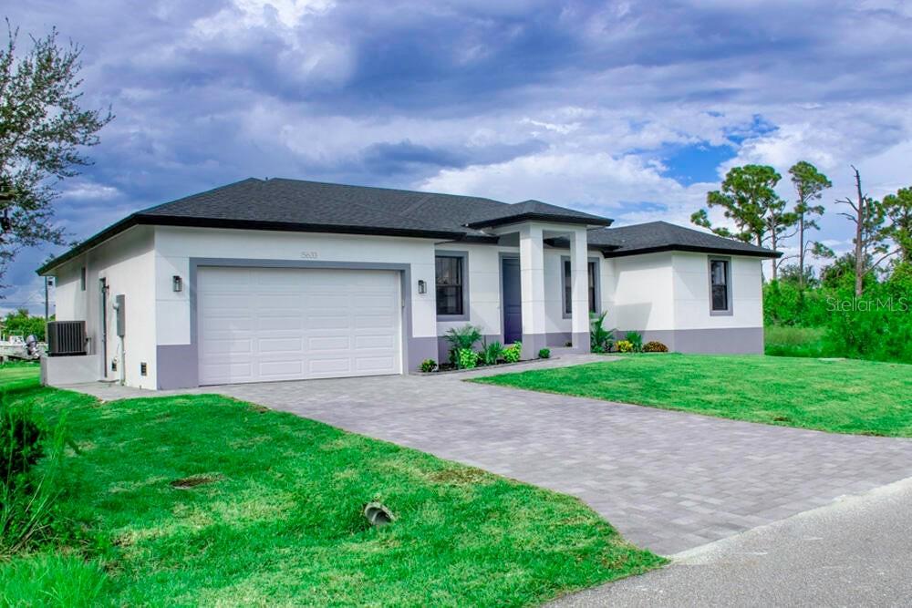 A single-story house with a white exterior, gray trim, and a paved driveway — 15633 LAKELAND CIRCLE, PORT CHARLOTTE, FL