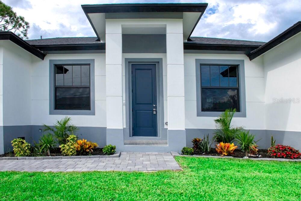 The exterior of a modern house features a blue front door and gray trim — 15633 LAKELAND CIRCLE, PORT CHARLOTTE, FL