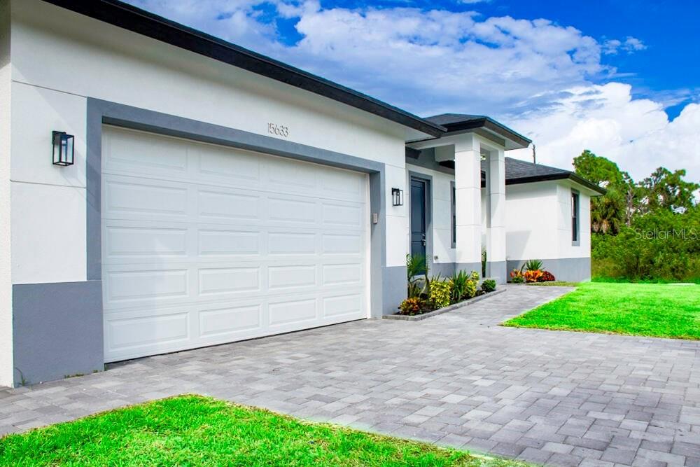 A modern house exterior features a white garage, gray trim, and a paved driveway — 15633 LAKELAND CIRCLE, PORT CHARLOTTE, FL