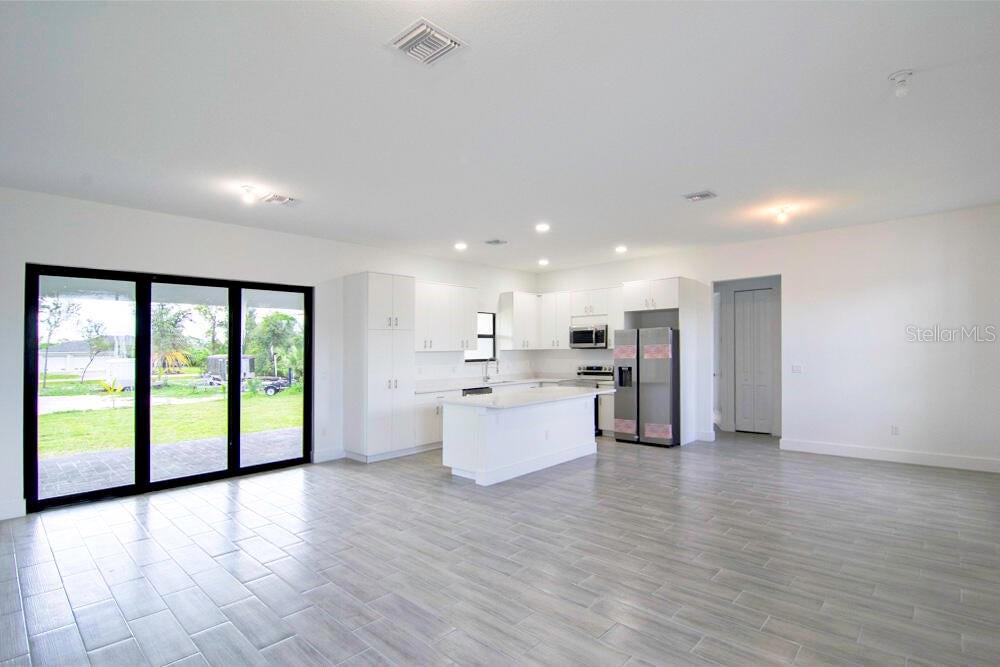 A modern kitchen with white cabinetry, a center island, and gray tile flooring — 15633 LAKELAND CIRCLE, PORT CHARLOTTE, FL