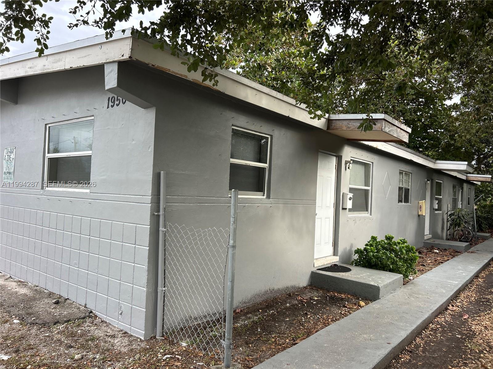 A gray, single-story concrete block building features multiple white doors and windows under overhanging eaves — 1950 Washington Ave # 2, Opa-Locka FL 33054, OPA-LOCKA, FL