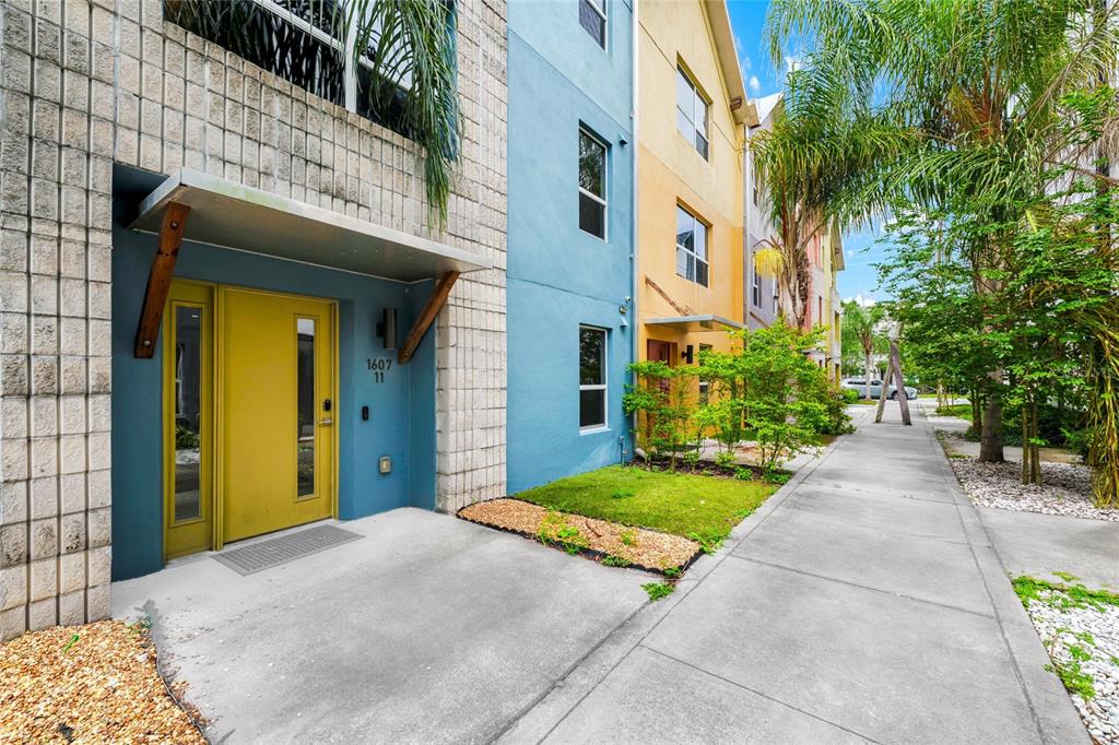 A bright yellow front door stands at the entrance of a blue multi-story townhouse — 1607 WOODWARD STREET UNIT 11, ORLANDO, FL