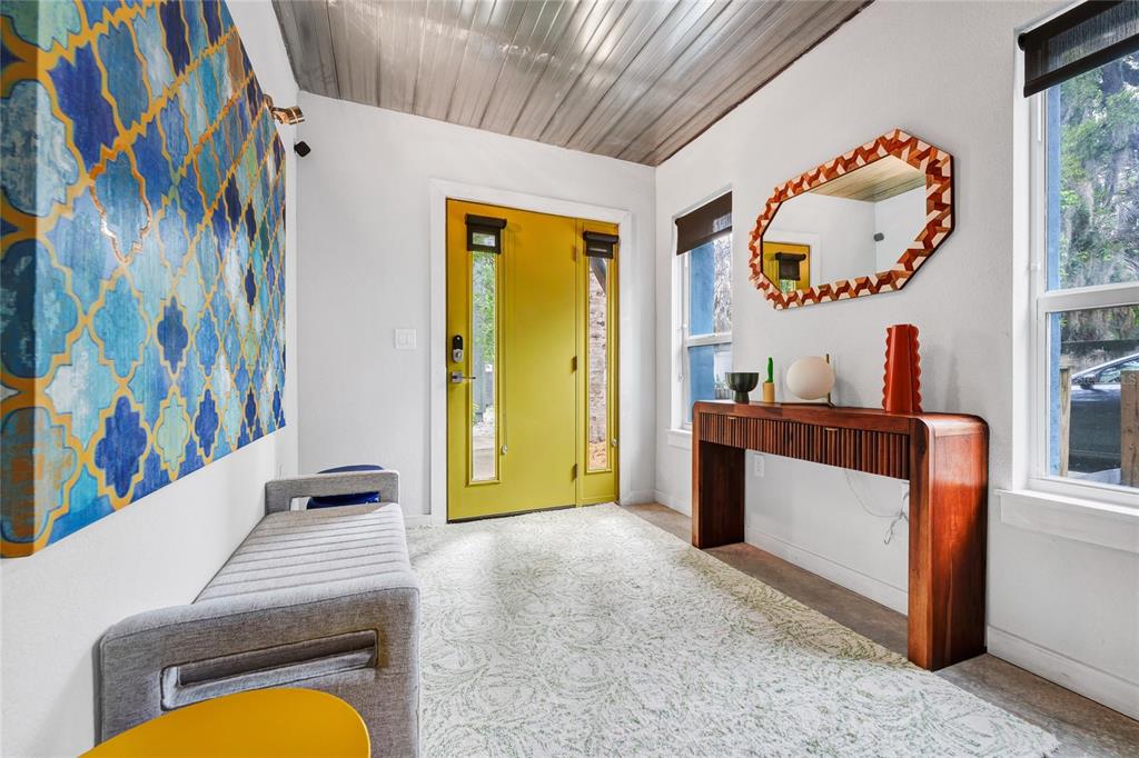 An entryway features a yellow front door, a gray bench, a wooden console table, and a mirror — 1607 WOODWARD STREET UNIT 11, ORLANDO, FL