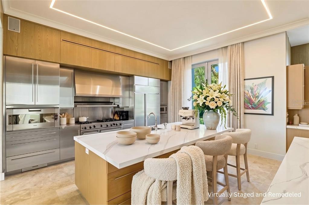 A modern kitchen features wood cabinetry, stainless steel appliances, and a white marble-topped island — 3315 BAY SHORE ROAD, SARASOTA, FL