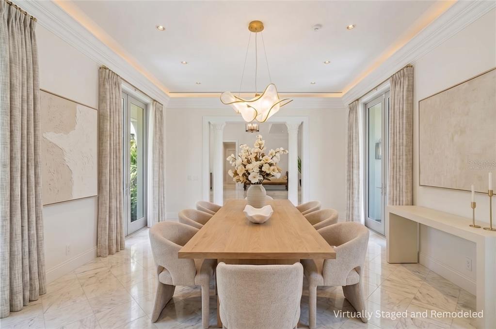 A dining room with a wooden table, upholstered chairs, marble floors, and a modern chandelier — 3315 BAY SHORE ROAD, SARASOTA, FL