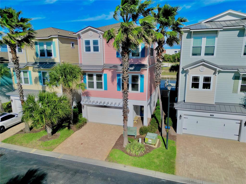 An aerial view shows a three-story pink house situated between two other residential homes — 2727 MORNING LIGHT COURT, FLAGLER BEACH, FL