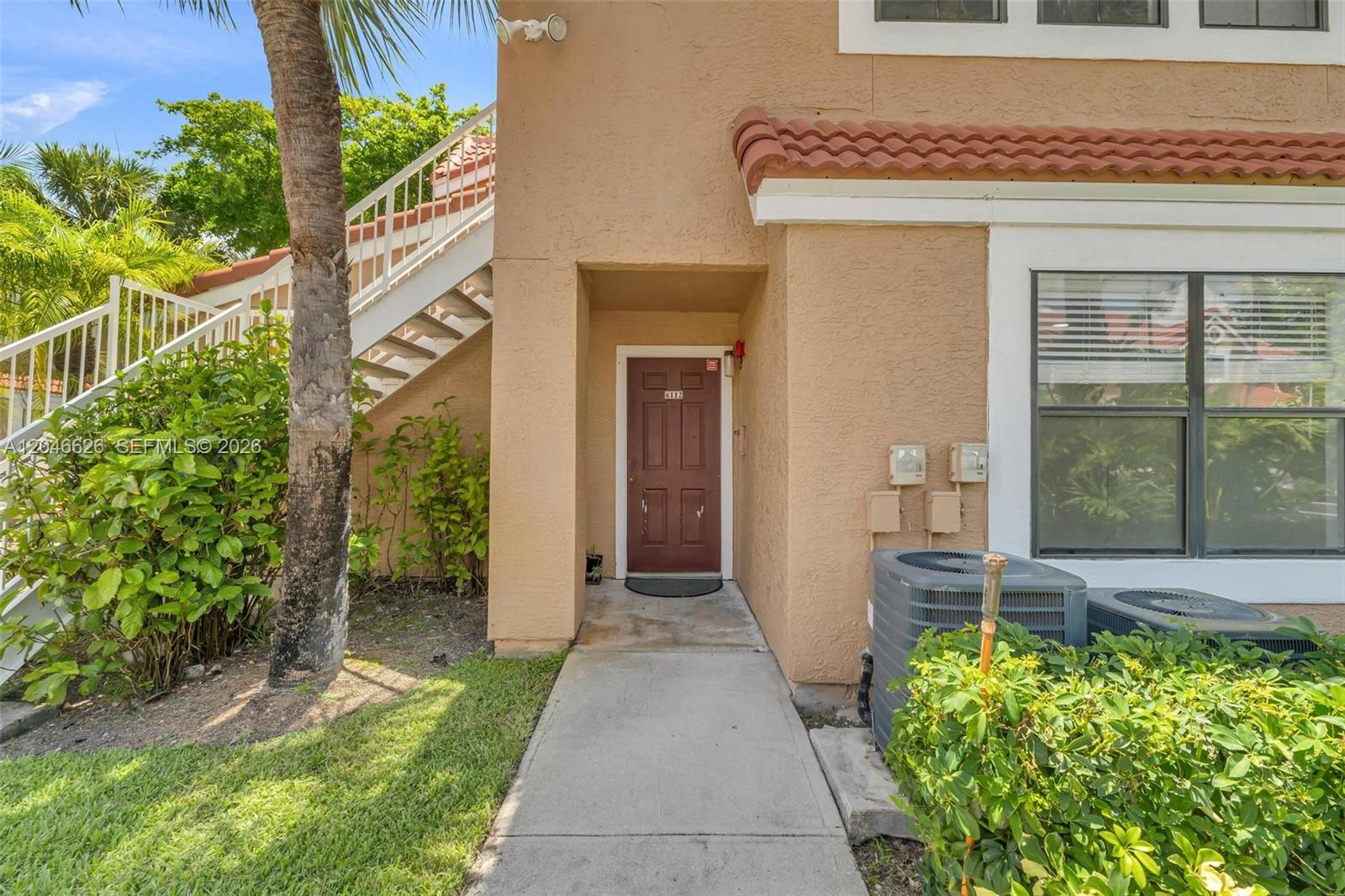 The exterior of a tan stucco building features a brown front door and outdoor stairs — 15560 SW 104th Ter # 6112, Miami FL 33196, MIAMI, FL