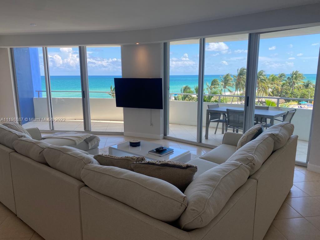 A living room with a large sectional sofa faces a wall-mounted television and ocean views — 5151 Collins Ave # 531, Miami Beach FL 33140, MIAMI BEACH, FL