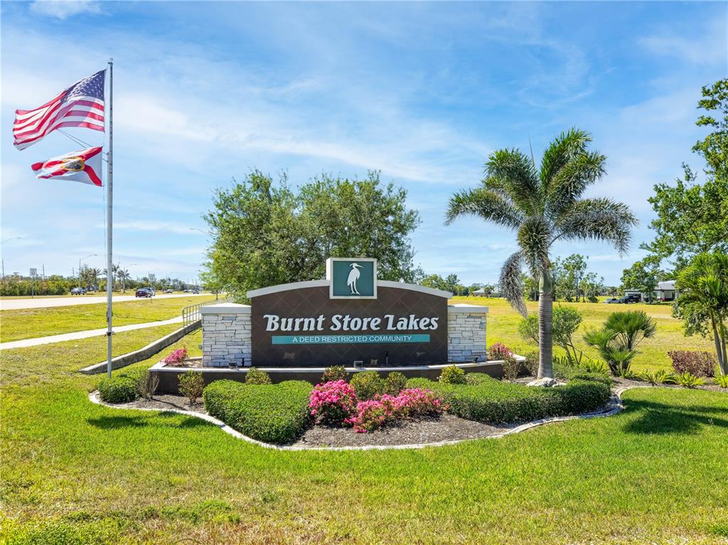 A stone and dark panel sign for Burnt Store Lakes stands in a landscaped yard — 17240 CAPE HORN BOULEVARD, PUNTA GORDA, FL