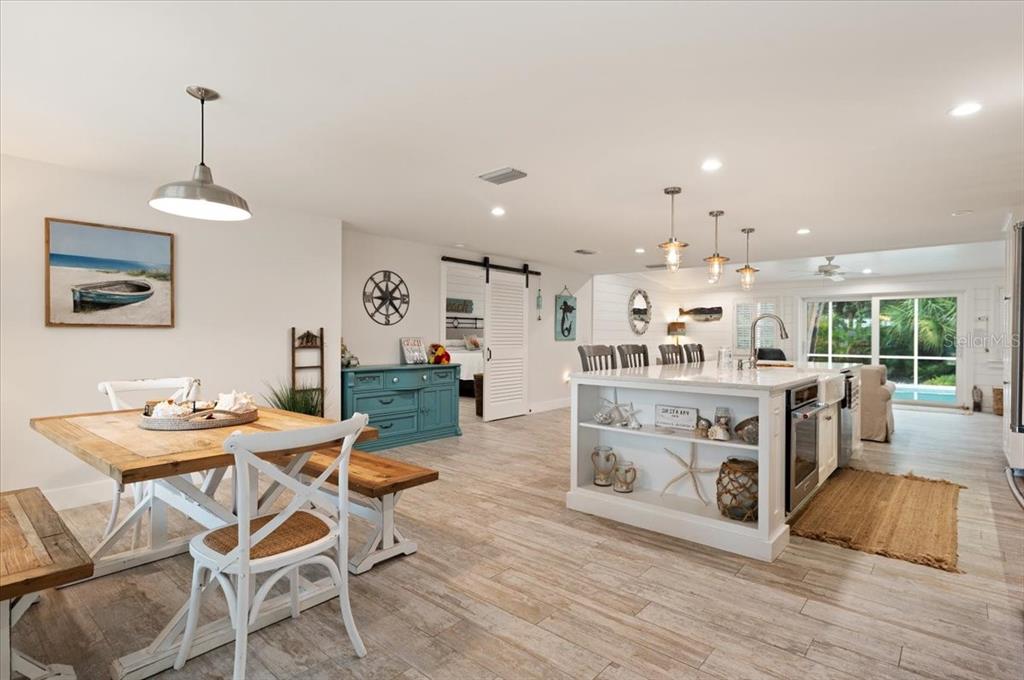 An open-concept kitchen and dining area features wood-look tile flooring and coastal-style decor — 5125 SANDY BEACH AVENUE, SARASOTA, FL