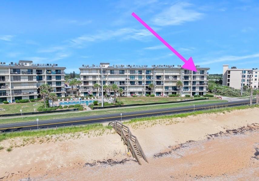 An aerial view shows a multi-story beachfront condominium complex with a pink arrow pointing upward — 2700 OCEAN SHORE BOULEVARD UNIT 518, ORMOND BEACH, FL