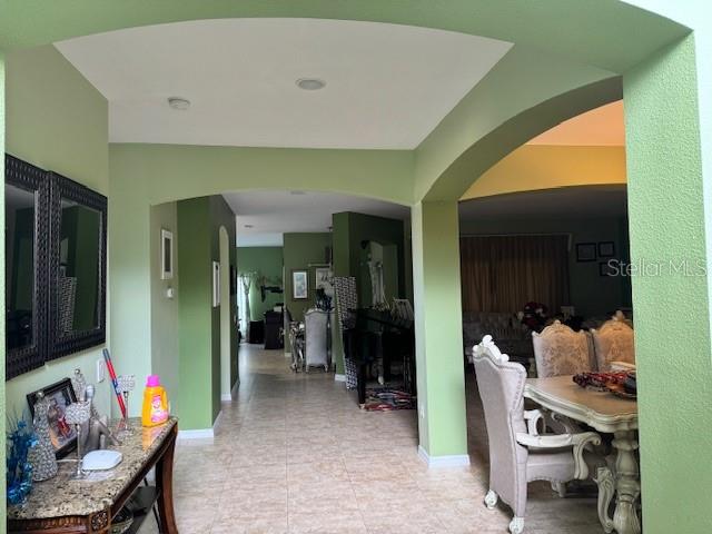 A view through an arched entryway into a dining room and a hallway with green walls — 3830 GOLDEN FEATHER WAY, KISSIMMEE, FL