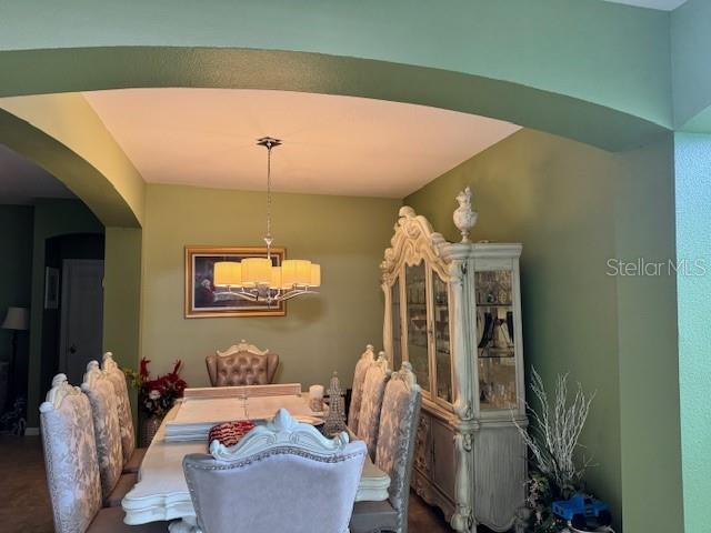 A dining room features a light-colored table, upholstered chairs, a china cabinet, and a chandelier — 3830 GOLDEN FEATHER WAY, KISSIMMEE, FL