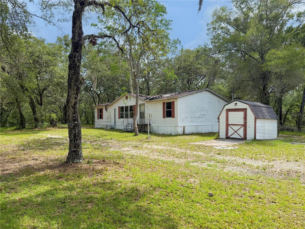 A single-story mobile home with white siding sits on a grassy lot with a shed — 8598 N APPENINES POINT, DUNNELLON, FL